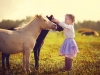 Girl in jockey boots caressing her pony