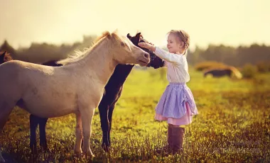 Girl in jockey boots caressing her pony