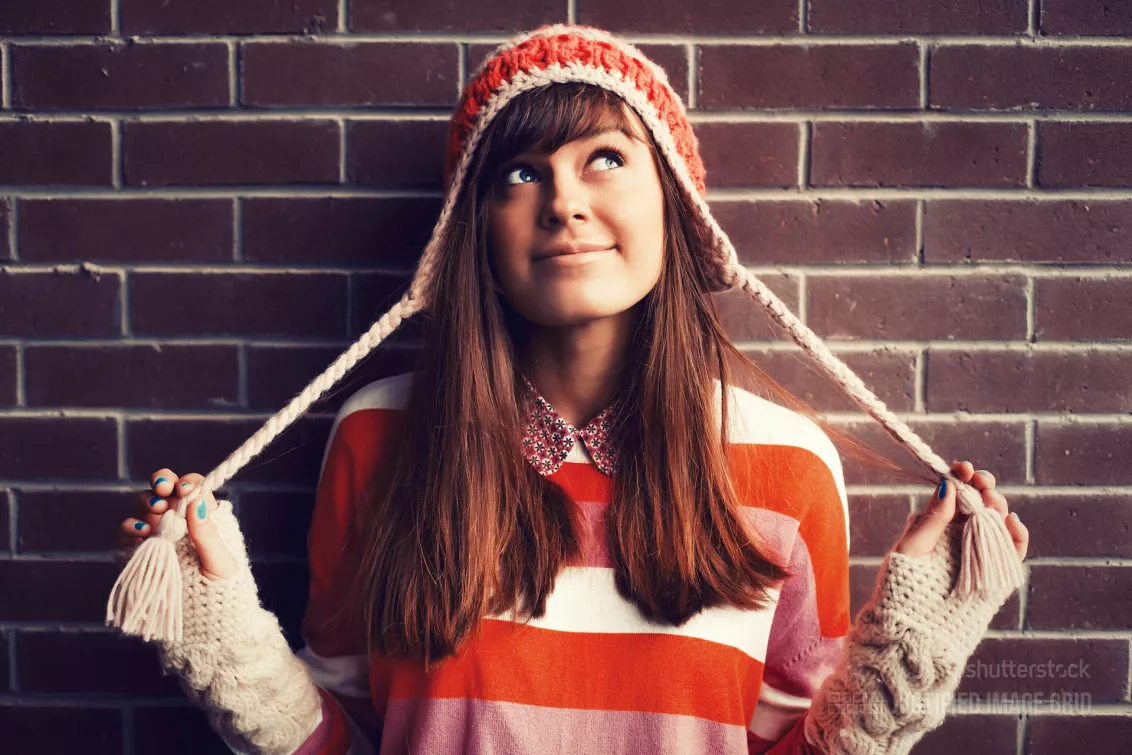 Smiling girl in red against brick wall