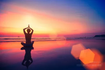 Silhouette of woman sitting on sea coast