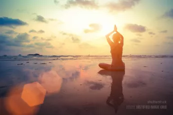 Young woman practicing yoga on the beach