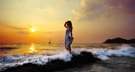 Young woman standing on rock in sea