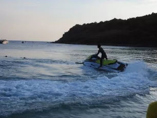 DSCN1038.JPG: Riding the last light, a lone jet skier cuts through the calm waters as evening falls near a tree-lined shore.