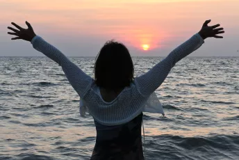 DSC_3521: a woman standing on a beach with her arms outstretched