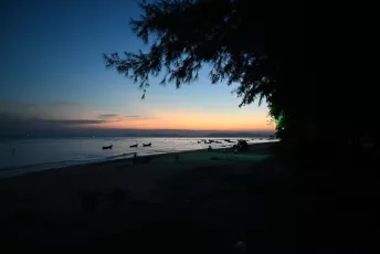 DSC_8318: Twilight serenity, a quiet beach as fishing boats drift on the calm water beneath the last glow of sunset.