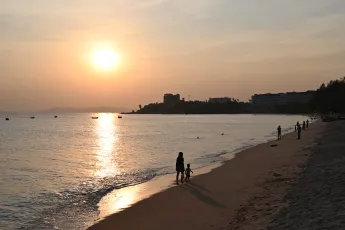 DSC_7749: Golden hour on the shore — a parent and child walk hand in hand as the sun sets over the tranquil sea.