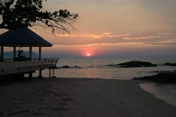 DSC_9015: Sunset over a quiet beach with a pavilion silhouetted against the glowing horizon.