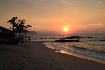 DSC_9007: Golden sun sinking over a peaceful beach, painting the waves and shoreline in soft amber light.