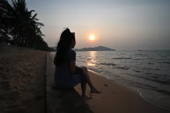 DSC_8631: a woman sitting on the beach watching the sunset