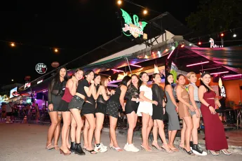 DZ6_1010: A lively group of friends posing together on a bustling, neon-lit street at night, dressed up for a fun night out.