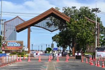 DFC_1436: A large wooden archway marks the entrance to a seaside promenade, with traffic cones and barriers guiding cars toward the beach beyond.