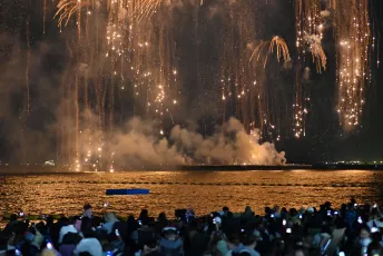 DFC_3862: A crowd of spectators watches golden fireworks cascade over the water, their reflections shimmering on the surface as sparks fall from the night sky.