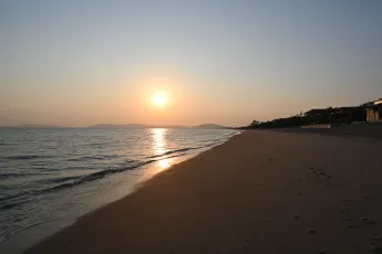 DZ6_2664: Golden hour hush, footprints lead to the setting sun over a tranquil shoreline.