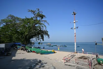 DFC_4517: Quiet fishing boats resting on a sunny, sandy shore beneath a clear blue sky.