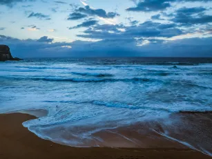 Seaside Sunrise with rolling waves and rain clouds