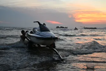 DFC_5144: Sunset launch, a jet ski is pushed into the waves off Pattaya as the sky glows orange.