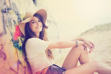 Girl smiles in hat against urban wall on the beach
