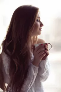 Young woman enjoying morning tea with closed eyes